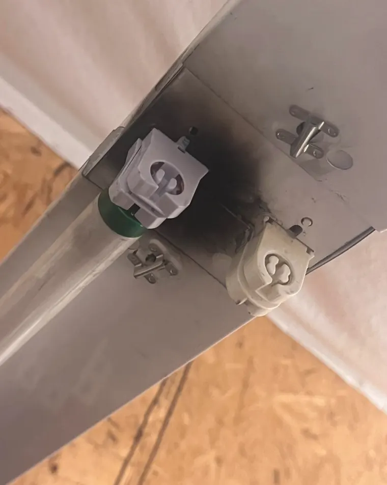 Close-up of scorched sockets on a fluorescent light fixture