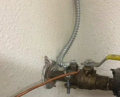 Copper ground wire at a water pipe clamp beside a valve
