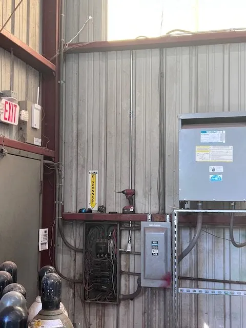 Electrical panels and a disconnect on the wall of a steel shop building