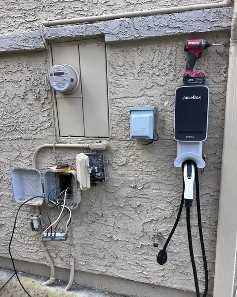 Stucco wall crowded with the old meter, an EV charger, an outlet and junction boxes